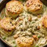 A bowl of chicken pot pie with biscuits.