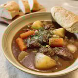 A bowl of beef stew with carrots and potatoes.