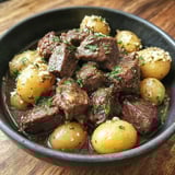 A bowl of beef and potatoes.